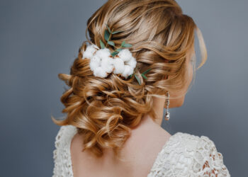 Rear view close-up of the finished wedding hairstyles in the form of winter bride with cotton flowers decoration