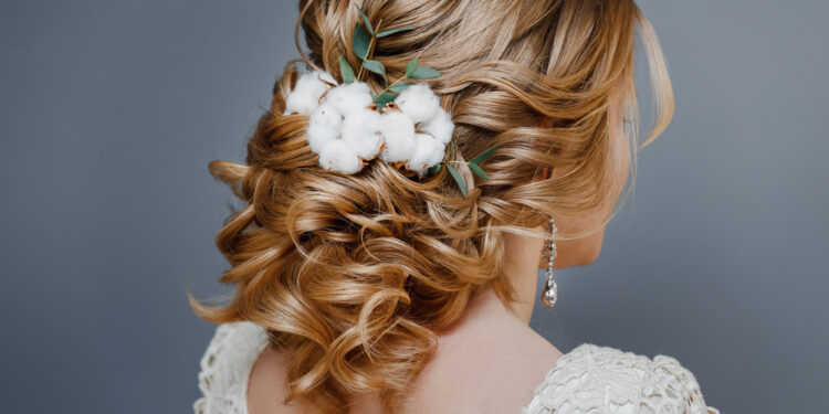 Rear view close-up of the finished wedding hairstyles in the form of winter bride with cotton flowers decoration